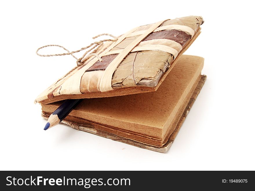 Old handmade paper notebook made from natural materials with blue pencil inside isolated on white background. Close-up. Old handmade paper notebook made from natural materials with blue pencil inside isolated on white background. Close-up