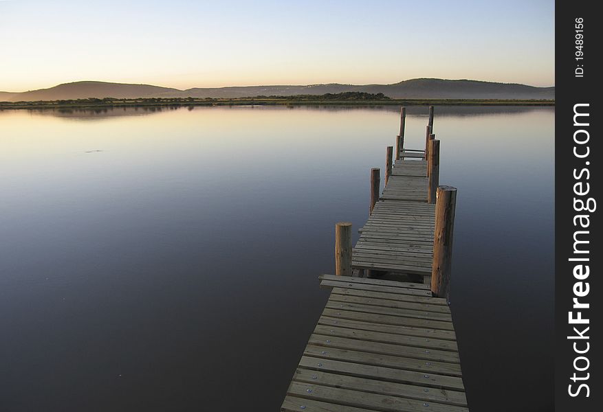 Old wooden jetty on a calm river, early morning. Old wooden jetty on a calm river, early morning