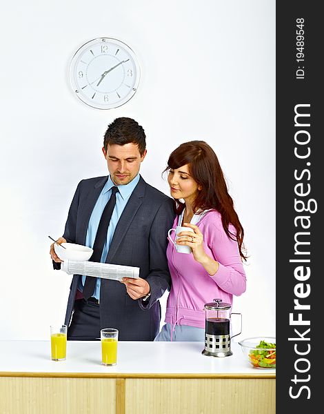 Businessman reading newspaper with his wife in kitchen before go to work. Businessman reading newspaper with his wife in kitchen before go to work