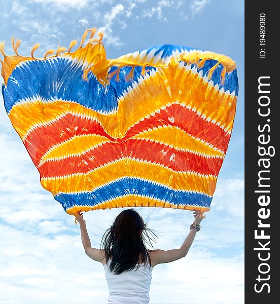 Pretty young sensuality girl is holding colorful batik sarong in front of moving boat during holiday