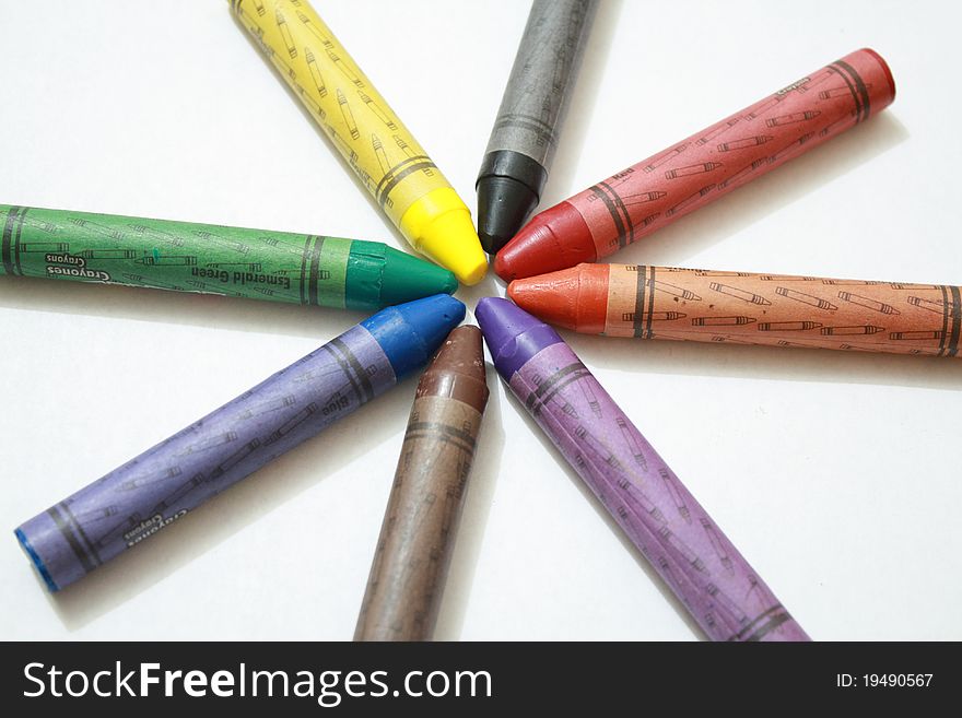 Eight crayons for kids, arranged in a circle shape.