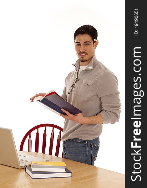 A man is standing by a table with a book and a laptop. A man is standing by a table with a book and a laptop.