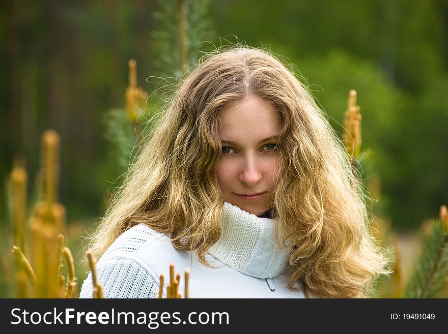 A young girl with long blond hair among young pines. A young girl with long blond hair among young pines