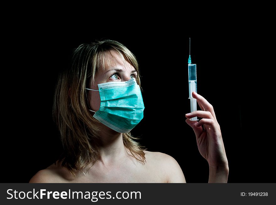 Young woman with a syringe on dark background