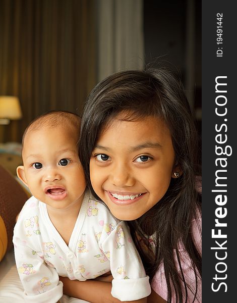 Portrait of asian ethnic little girl and baby on bed. Portrait of asian ethnic little girl and baby on bed