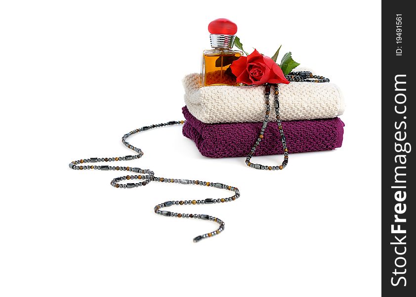 Perfume bottle,red rose  and beads with stacked towels on white background. Perfume bottle,red rose  and beads with stacked towels on white background