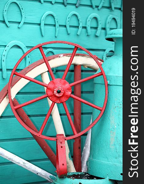 A detailed telephoto shot of a brightly painted wagon or carriage wheel with aqua painted horseshoes and wall in Nicaragua. A detailed telephoto shot of a brightly painted wagon or carriage wheel with aqua painted horseshoes and wall in Nicaragua.