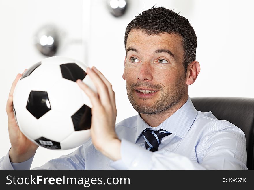 Young businessman in office with ball. Young businessman in office with ball