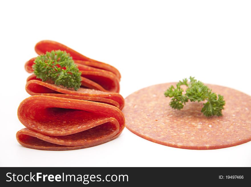 Paprika salami with parsley onto white background