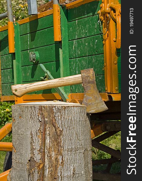 A trailer load with wood, before it an axe in log