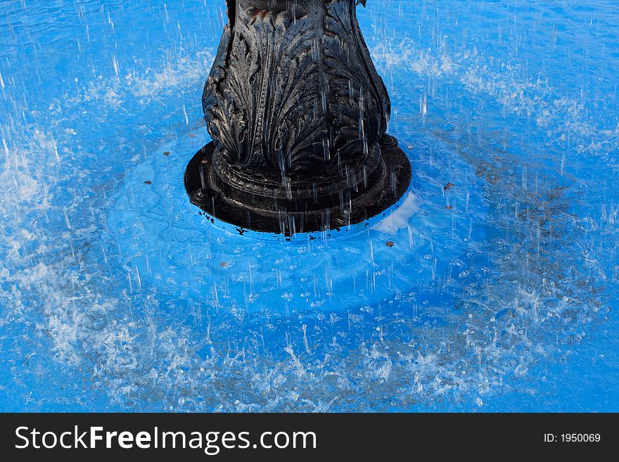 Water splashing around a fountain in a blue pool. Water splashing around a fountain in a blue pool.