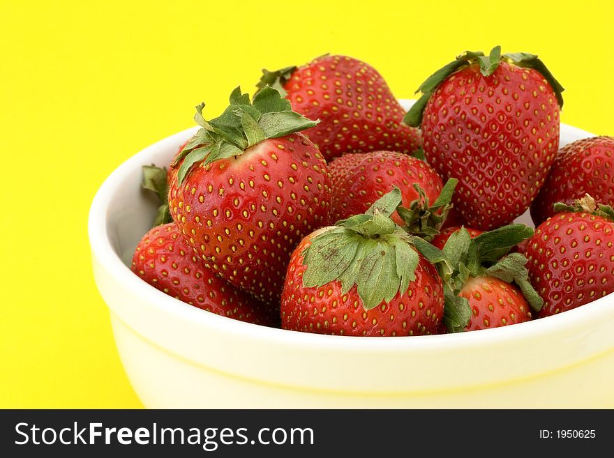 Close-up bowlof ripe strawberries in a white bowl on yellow background. Close-up bowlof ripe strawberries in a white bowl on yellow background