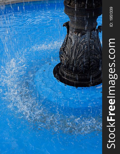 Water splashing around a fountain in a blue pool. Water splashing around a fountain in a blue pool.