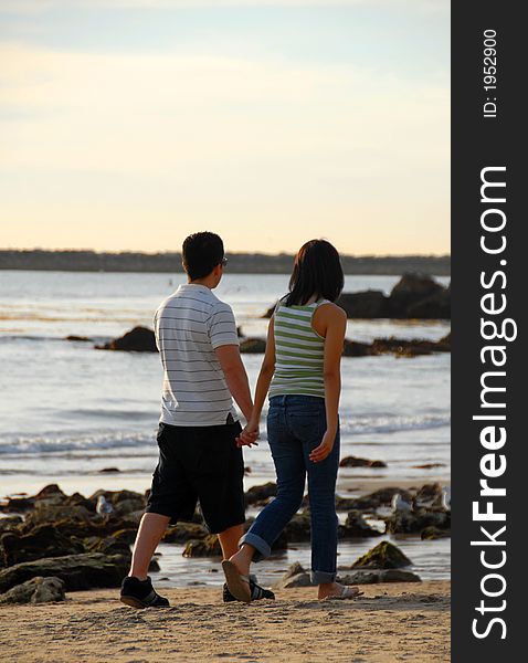 A couple is walking holding hands on the beach. A couple is walking holding hands on the beach