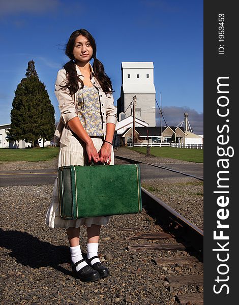 A stock image of a young woman in a rural setting waiting for a train. Suitcase. Portrait. A stock image of a young woman in a rural setting waiting for a train. Suitcase. Portrait.