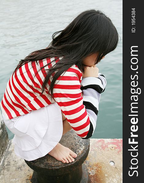 Different colored stripes worn by a young Asian girl squatting. Different colored stripes worn by a young Asian girl squatting