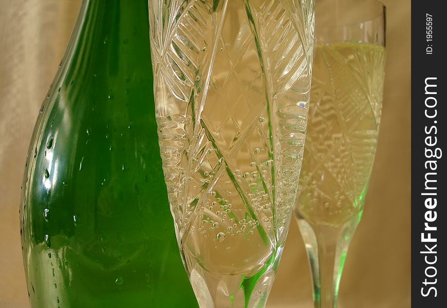 Close-up view of Champagne glasses with bottle on golden background