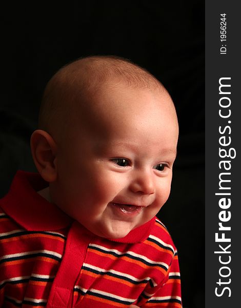 The face of a baby boy posing for the camera on a black background. The face of a baby boy posing for the camera on a black background.