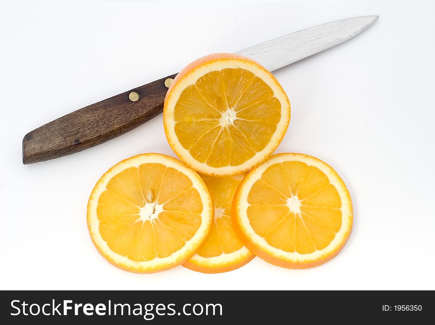 A sliced orange with knife on a white chopping board