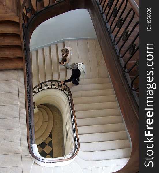 Spiral staircase in France looking down with a couple walking