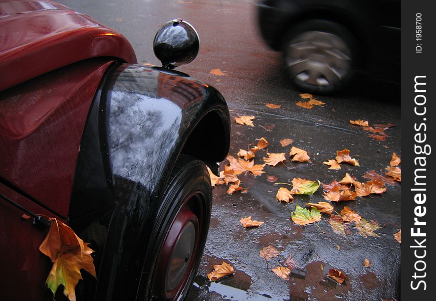 Autumnal street with old car and leaves.