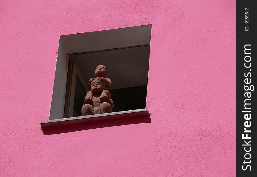 A statue in a window on a violet wall in Bosa, Sardinia, italy, in a sunny day