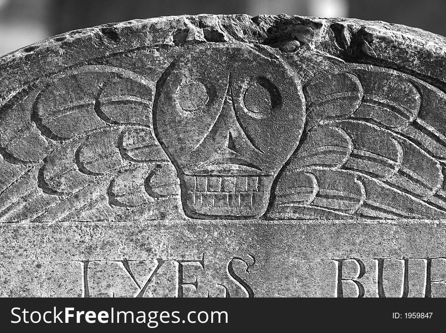 Detail of old head stone showing skull with wings. Detail of old head stone showing skull with wings