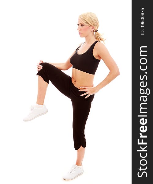 A young female dressed in black gym clothes performing a stretching exercise on isloated white background. A young female dressed in black gym clothes performing a stretching exercise on isloated white background