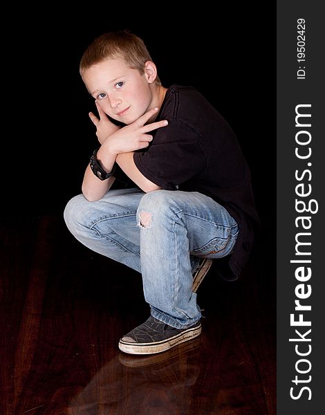 A photograph of a young boy with his arms crossed and his fingers in a peace sign.