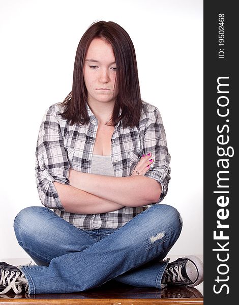 A photograph of a teenage girl sitting with her legs and arms crossed pouting. A photograph of a teenage girl sitting with her legs and arms crossed pouting.