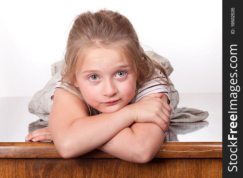 A photograph of a young girl lying on a desk looking forward with her big eyes. A photograph of a young girl lying on a desk looking forward with her big eyes.