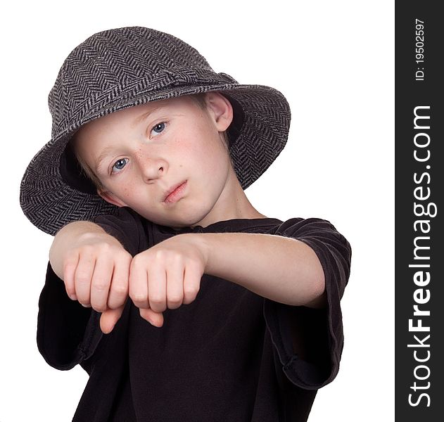 A photograph of a young boy with his knuckles showing while wearing his grey hat.
