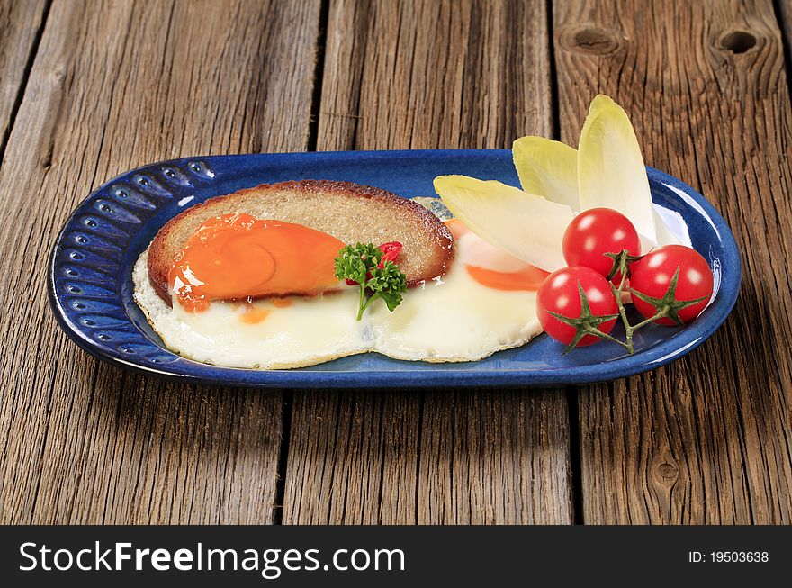 Fried egg and bread and vegetable garnish. Fried egg and bread and vegetable garnish