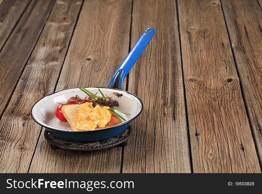 Scrambled eggs on toast and tomatoes in a pan