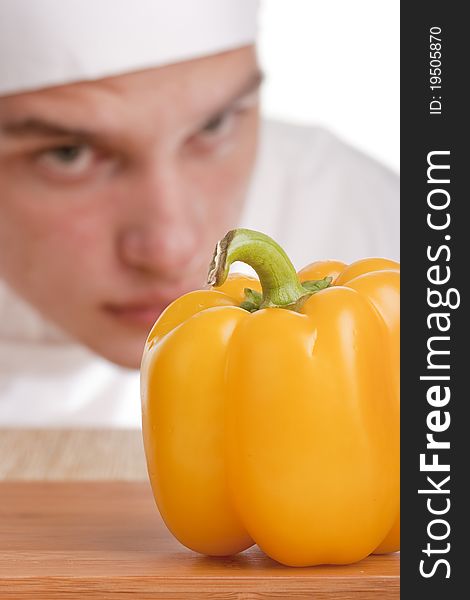 The young chef in chef's hat is considering a pepper. The young chef in chef's hat is considering a pepper.