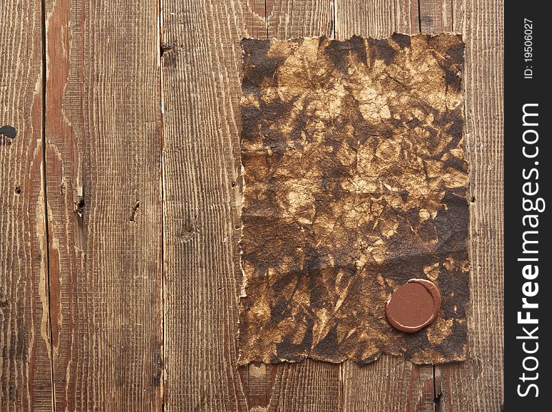 Old paper with a wax seal on brown wood texture with natural patterns