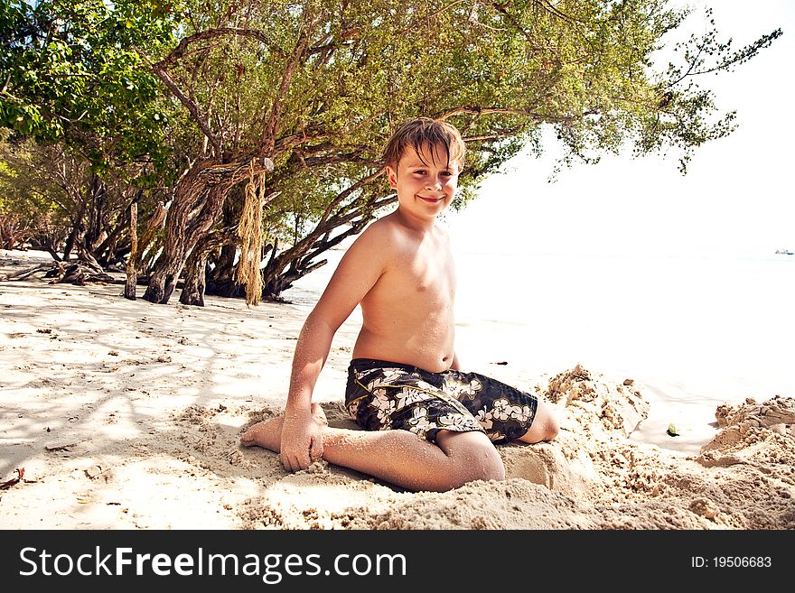 Happy young boy covered by fine sand at the beach. Happy young boy covered by fine sand at the beach