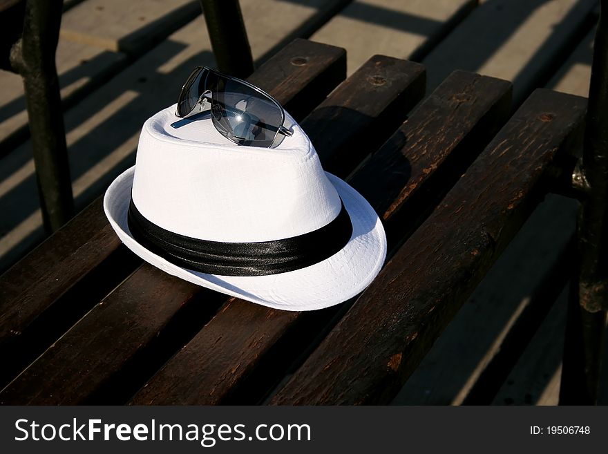 White hat with sunglasses on bench.