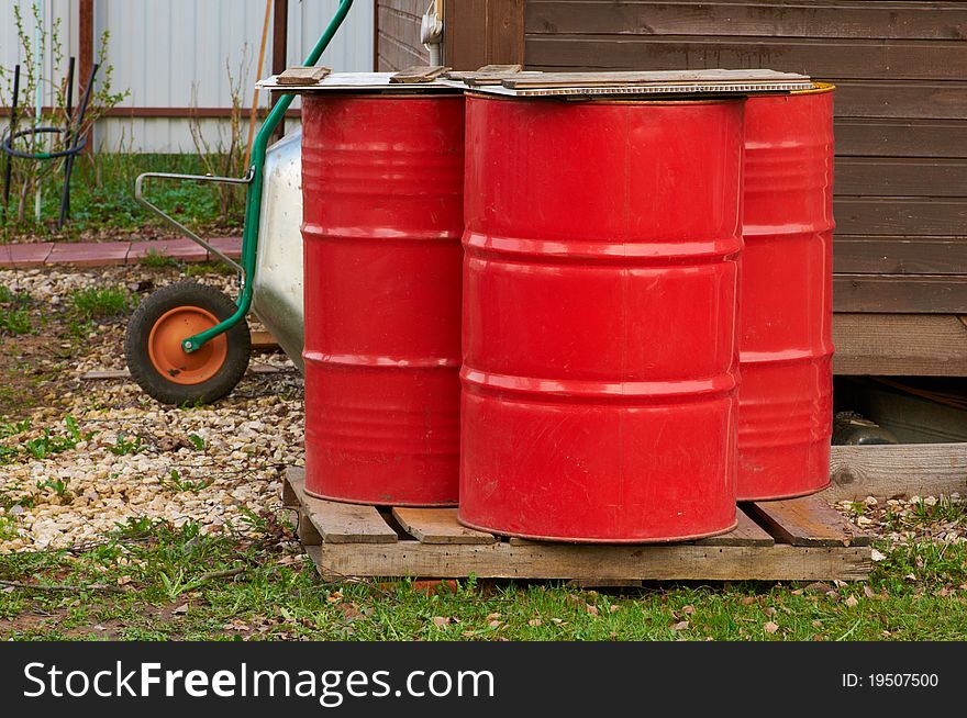 Three red fire barrels near wooden house. Three red fire barrels near wooden house