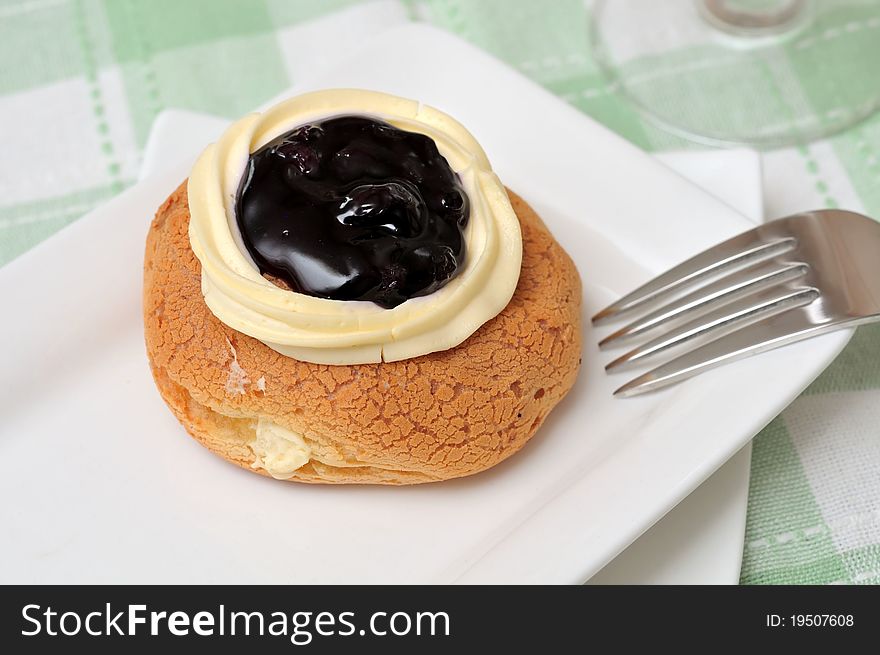 Fresh blueberry cheese doughnut on white plate with fork. Fresh blueberry cheese doughnut on white plate with fork.