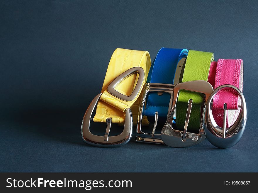 Few coloured leather belts in a row on dark background. Few coloured leather belts in a row on dark background