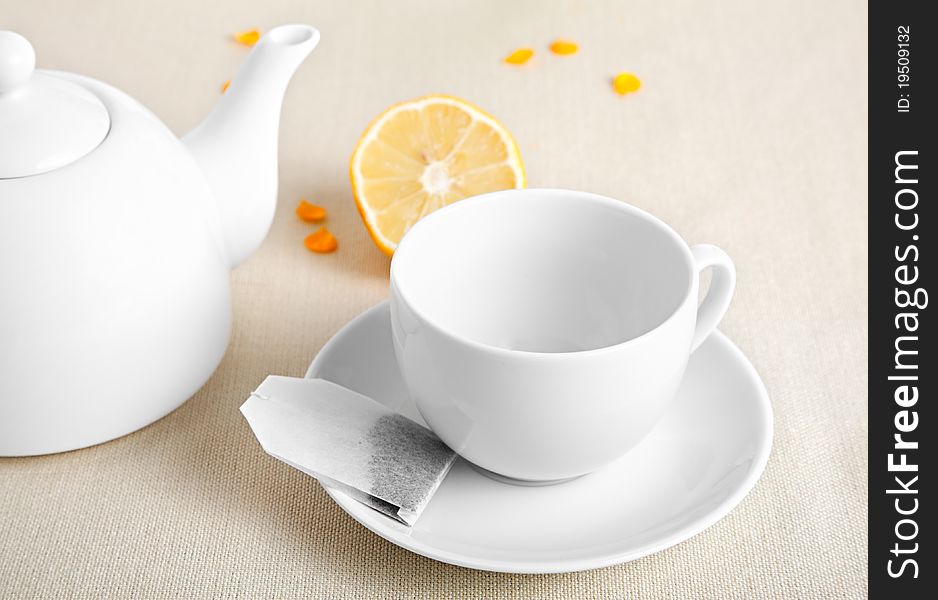 White cup with tea bag and teapot, on the table
