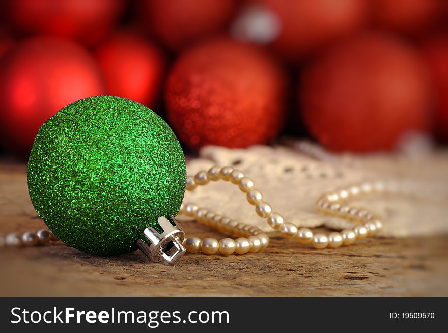 Red and green Christmas balls on an old vintage table with pearls