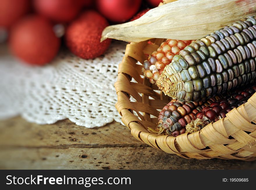 Ear of Indian corn in basket with Christmas balls in background