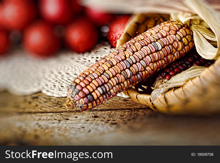 Ear of Indian corn in basket with Christmas balls in background