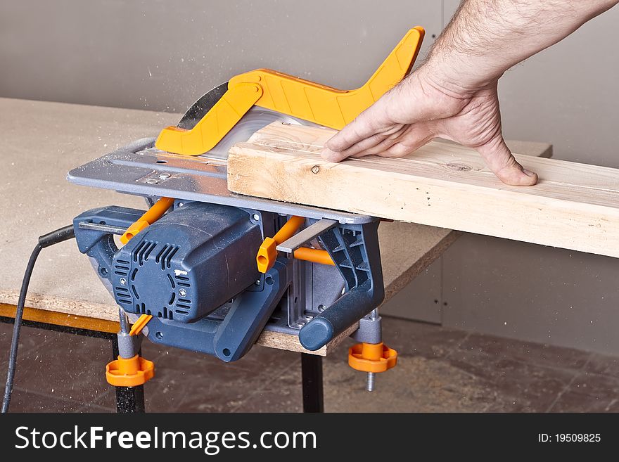 Close-up of a construction worker's hand and power tool while planing a piece of wood trim for a project. Close-up of a construction worker's hand and power tool while planing a piece of wood trim for a project.
