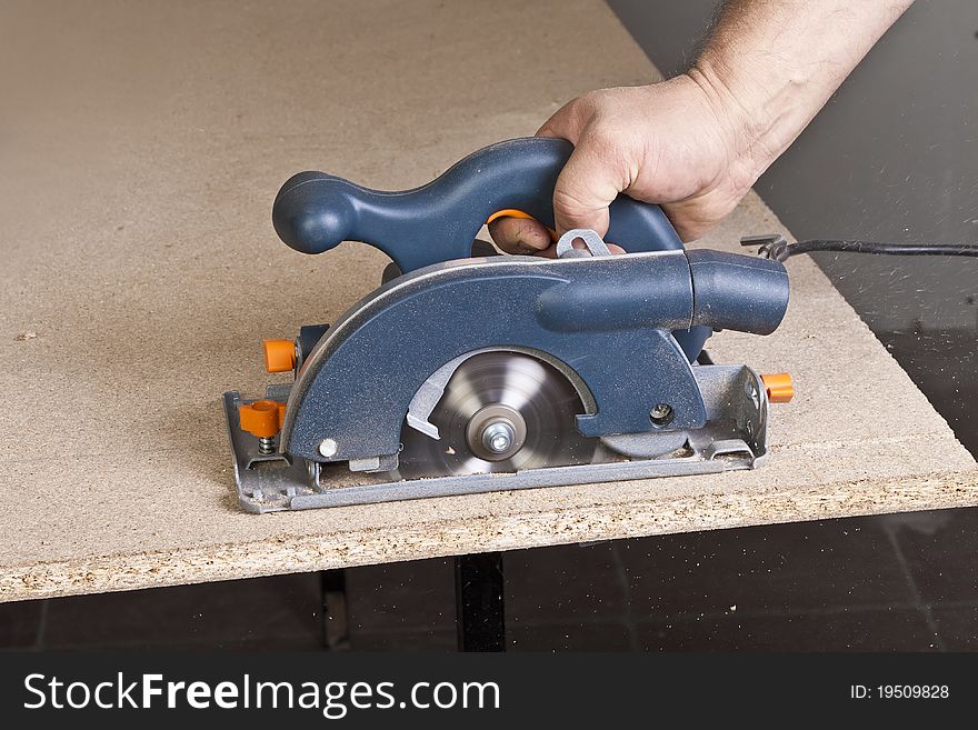 Close-up of a construction worker's hand and power tool while planing a piece of wood trim for a project. Close-up of a construction worker's hand and power tool while planing a piece of wood trim for a project.