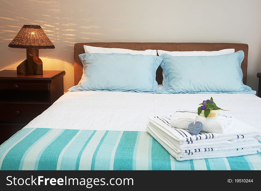 Beautiful bedroom interior with white sheets and striped towels