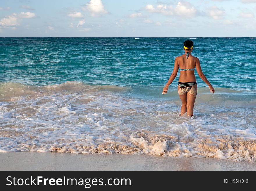 Tanned girls is standing in bright blue ocean under blue sky