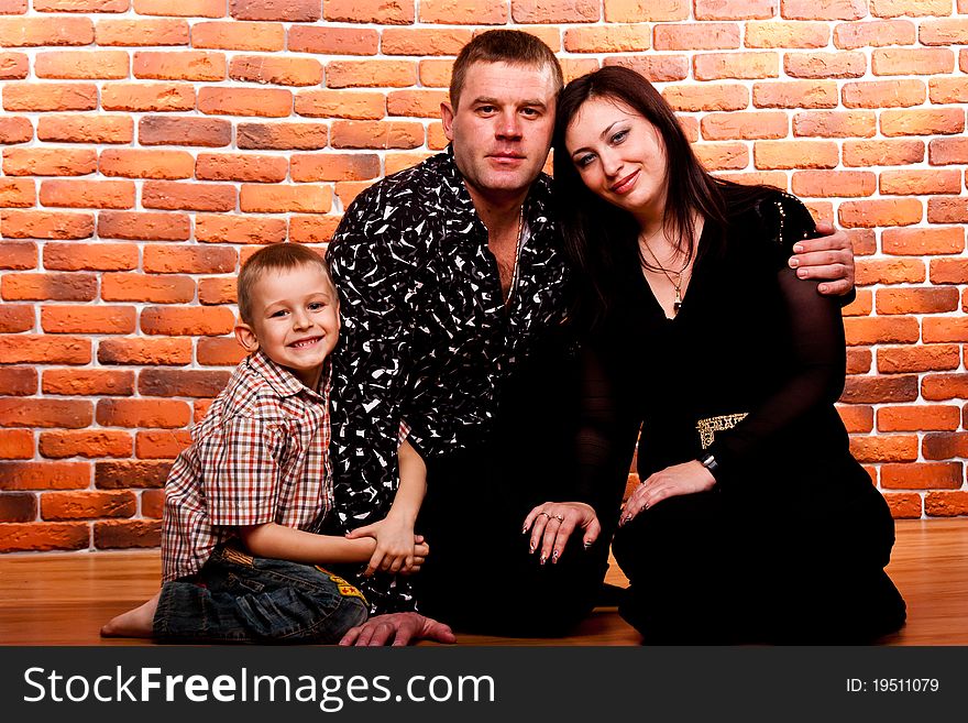 Happy family sitting against brick wall